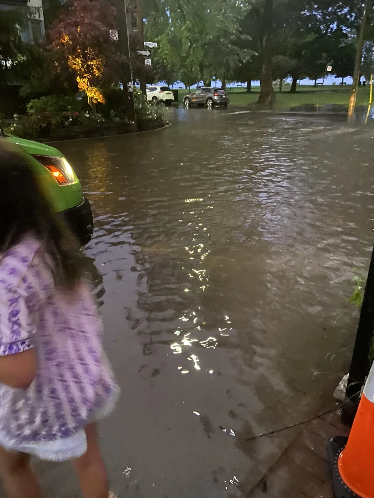 Floodwater covers Kippendavie Avenue beside parked cars, with a person standing in the water near the edge of the photo.